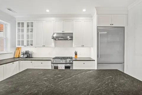 a kitchen with stainless steel appliances granite countertop a refrigerator and a stove top oven