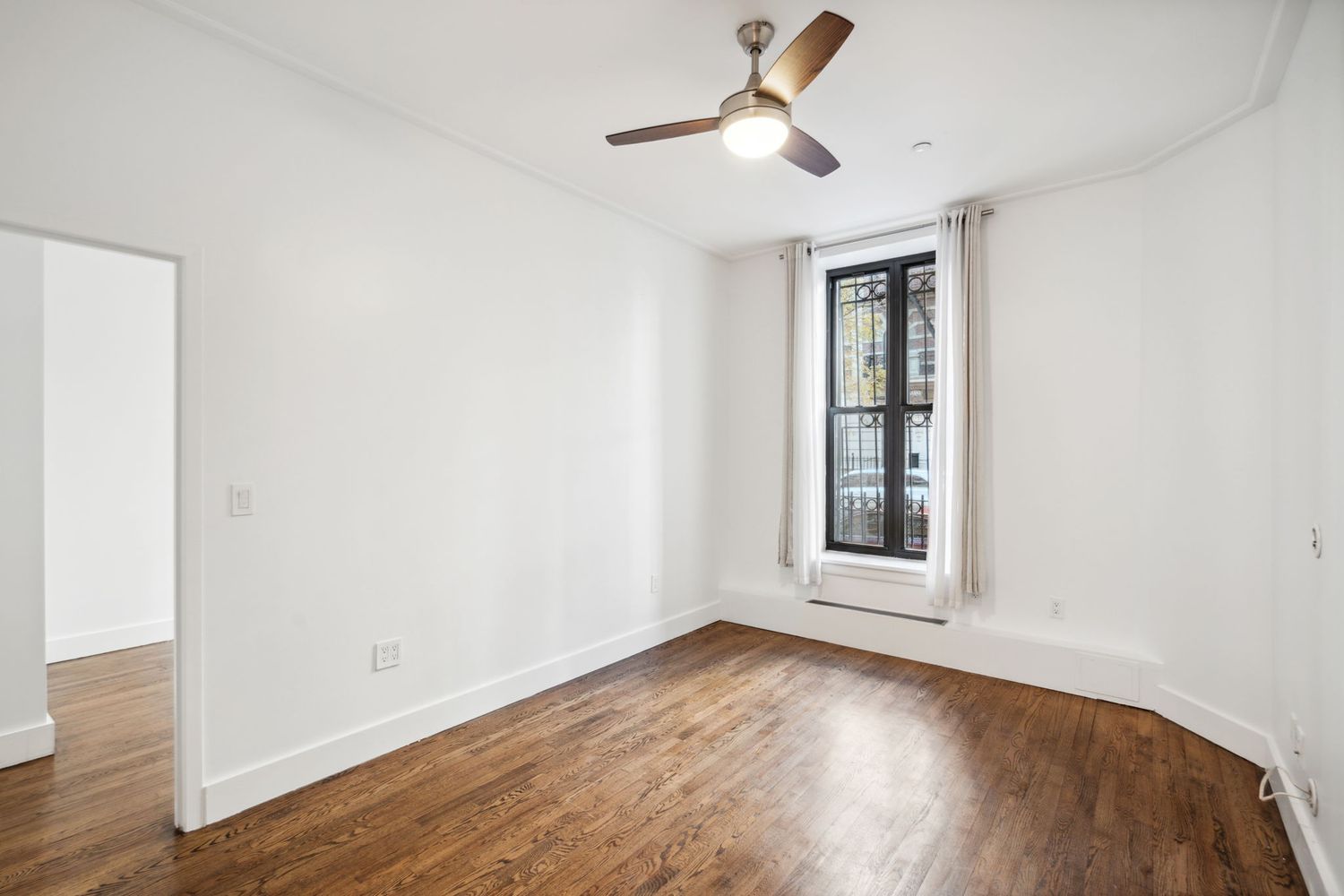 an empty room with wooden floor ceiling fan and windows