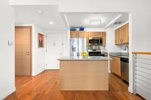 a kitchen with stainless steel appliances granite countertop a refrigerator a stove top oven a sink and dishwasher with wooden floor