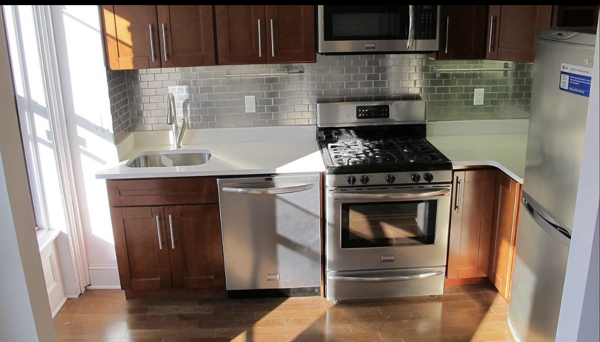 68 Downing Street, Unit 3 Brooklyn, NY 11238 - Photo 2 of 7 a kitchen with granite countertop wood cabinets and a stove top oven