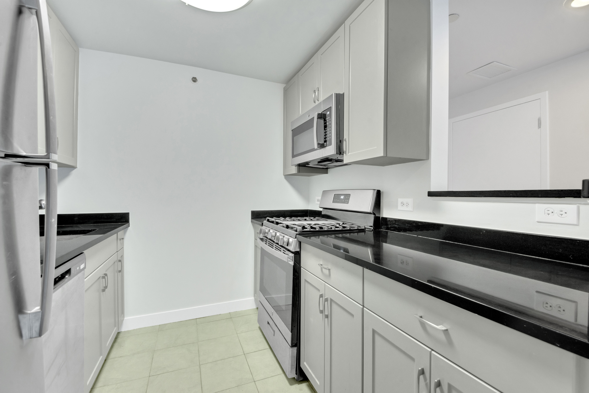 40 West 116th Street, Unit B205 Manhattan, NY 10026 - Photo 3 of 24 a kitchen with stainless steel appliances granite countertop a sink stove and microwave