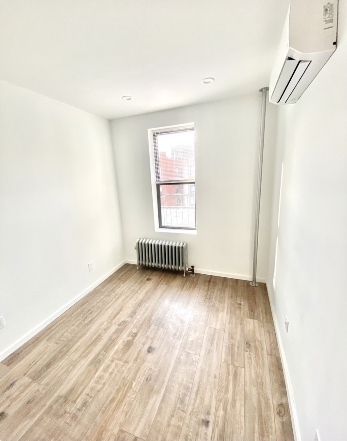 31-14 36th Street, Unit 3F Queens, NY 11106 - Photo 9 of 11 an empty room with wooden floor and windows
