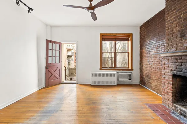 a view of an empty room with a window and wooden floor
