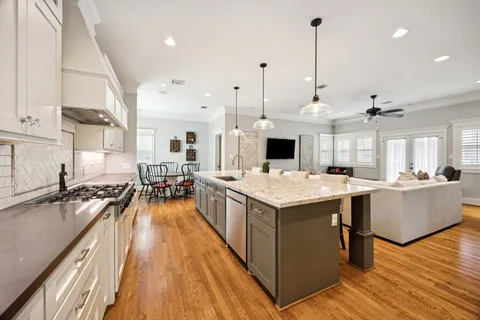 a view of a kitchen with kitchen island a stove a sink a center island and wooden floor