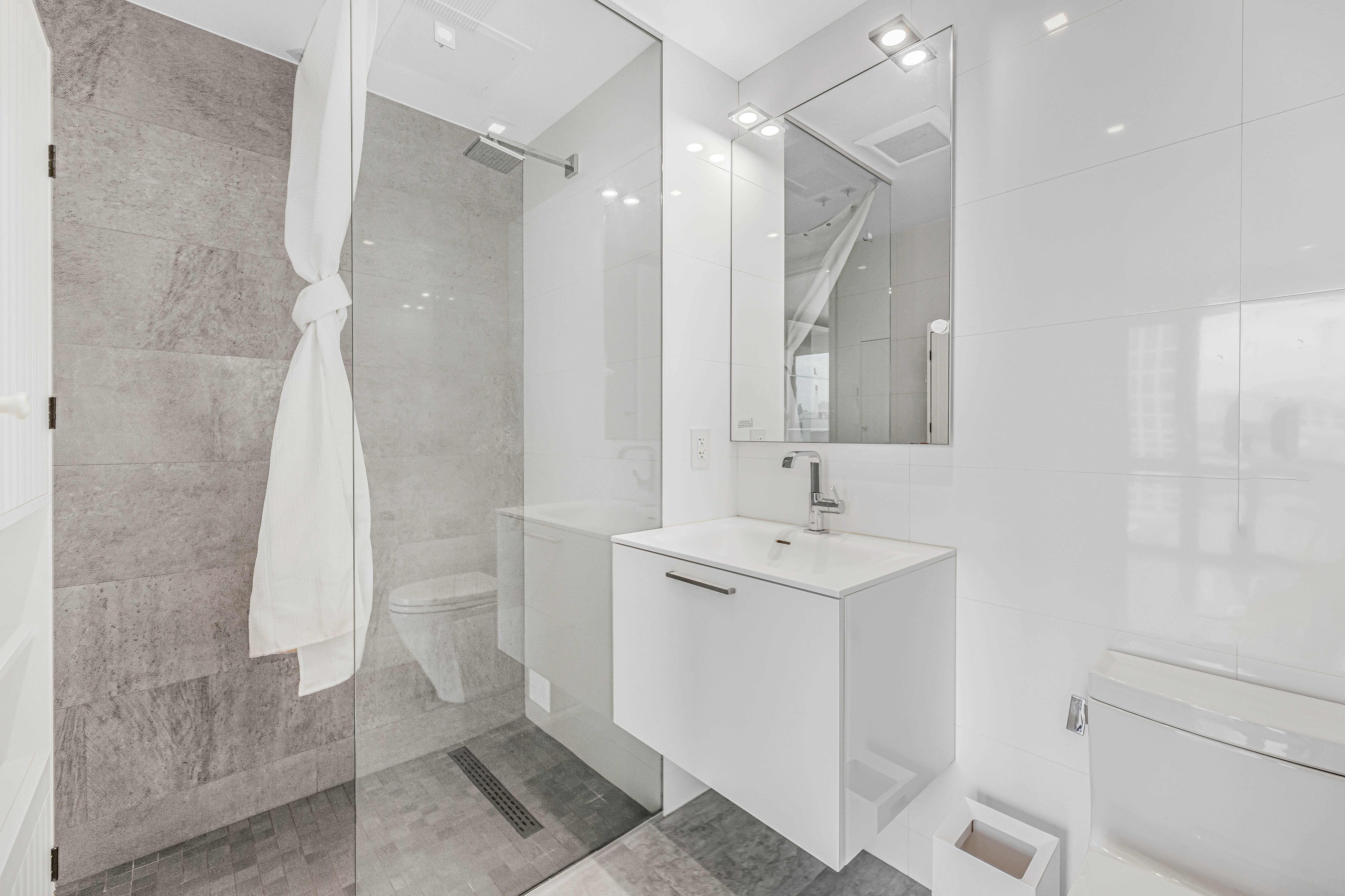 42-50 27th Street, Unit 9C Queens, NY 11101 - Photo 10 of 32 a bathroom with a sink a toilet and shower