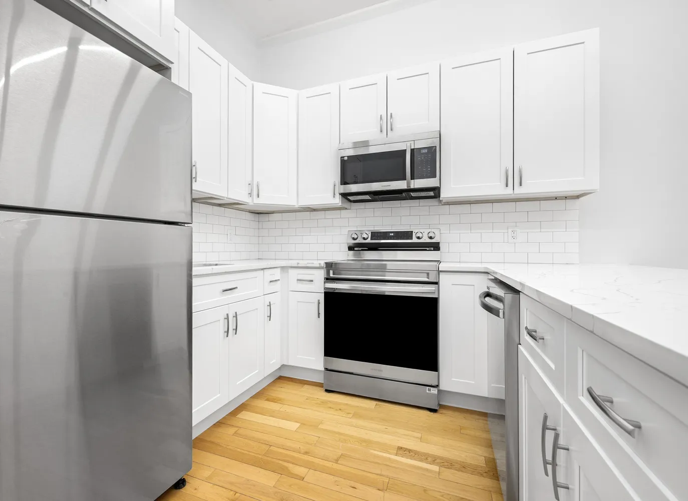 a kitchen with stainless steel appliances white cabinets and a refrigerator