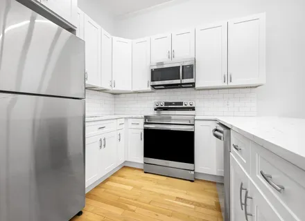 a kitchen with stainless steel appliances white cabinets and a refrigerator