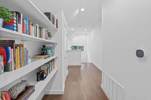a hallway with painting and a book shelf