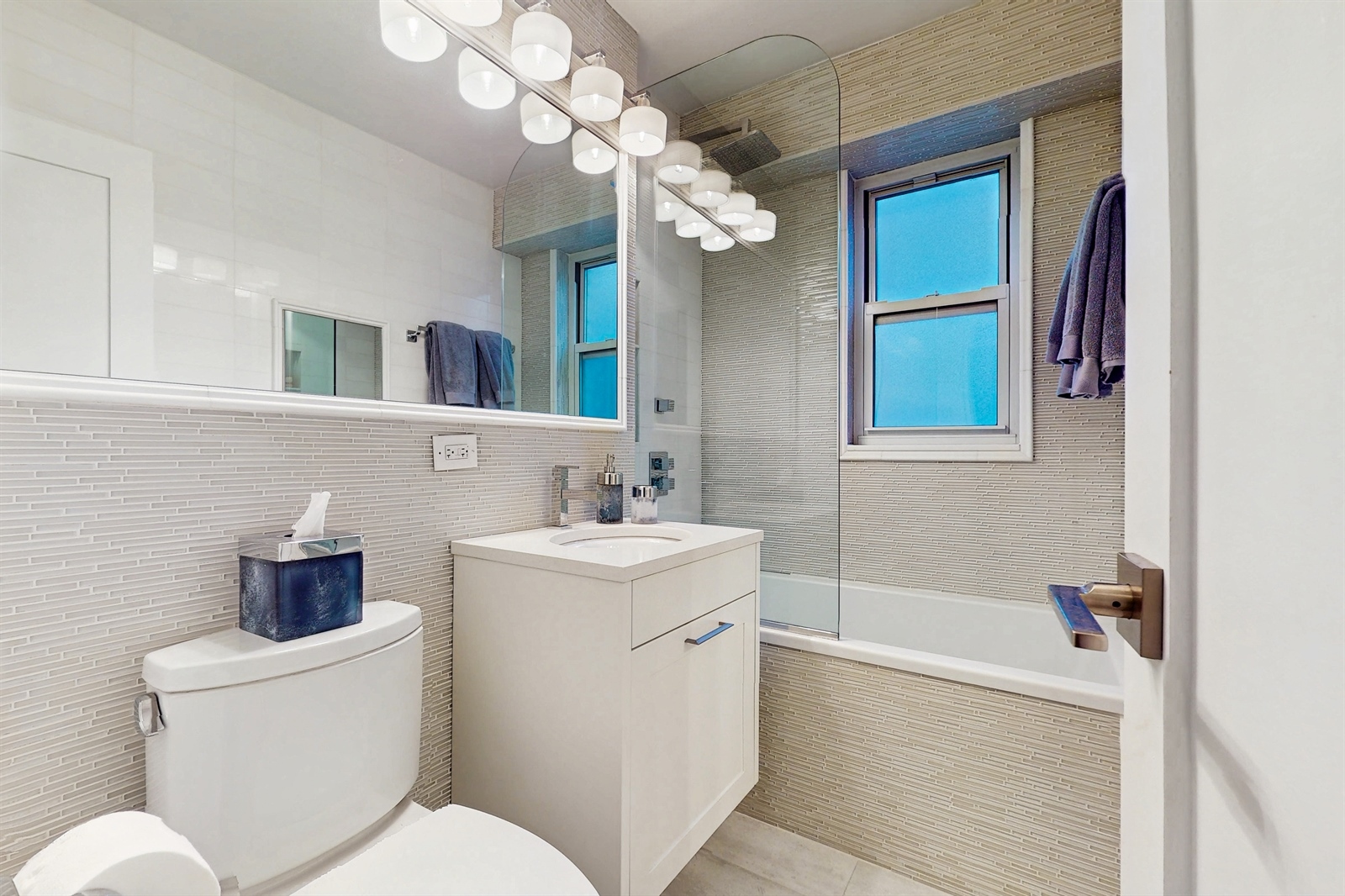 136 East 56th Street, Unit 16B Manhattan, NY 10022 - Photo 9 of 11 a bathroom with a toilet a sink a mirror and bathtub