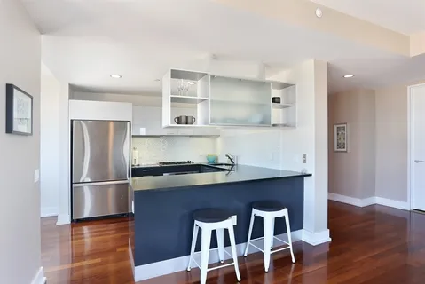 a kitchen with stainless steel appliances granite countertop a refrigerator a sink dishwasher and a stove with wooden floor