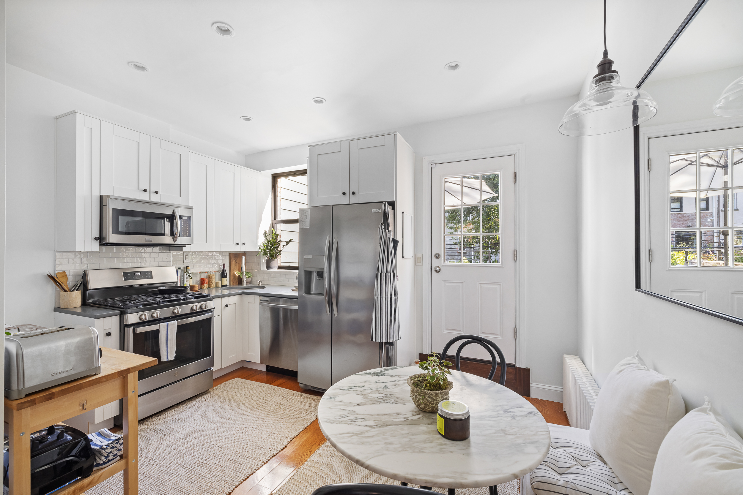 716 Monroe Street Brooklyn, NY 11221 - Photo 4 of 22 a kitchen with stainless steel appliances granite countertop a refrigerator a stove a sink dishwasher with a dining table and chairs