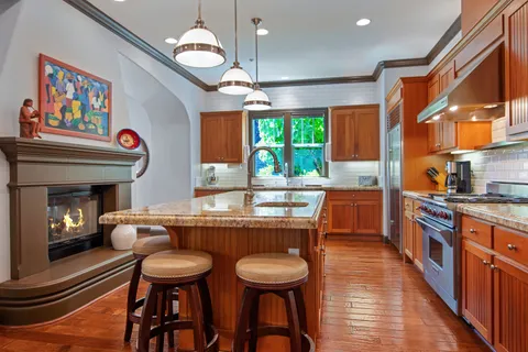 a kitchen with stainless steel appliances granite countertop a stove a sink dishwasher and a dining table with garden view