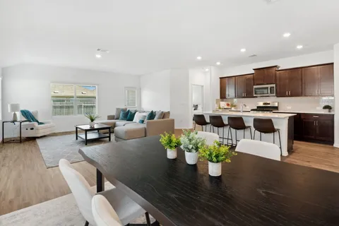 a living room with furniture kitchen area and a wooden floor