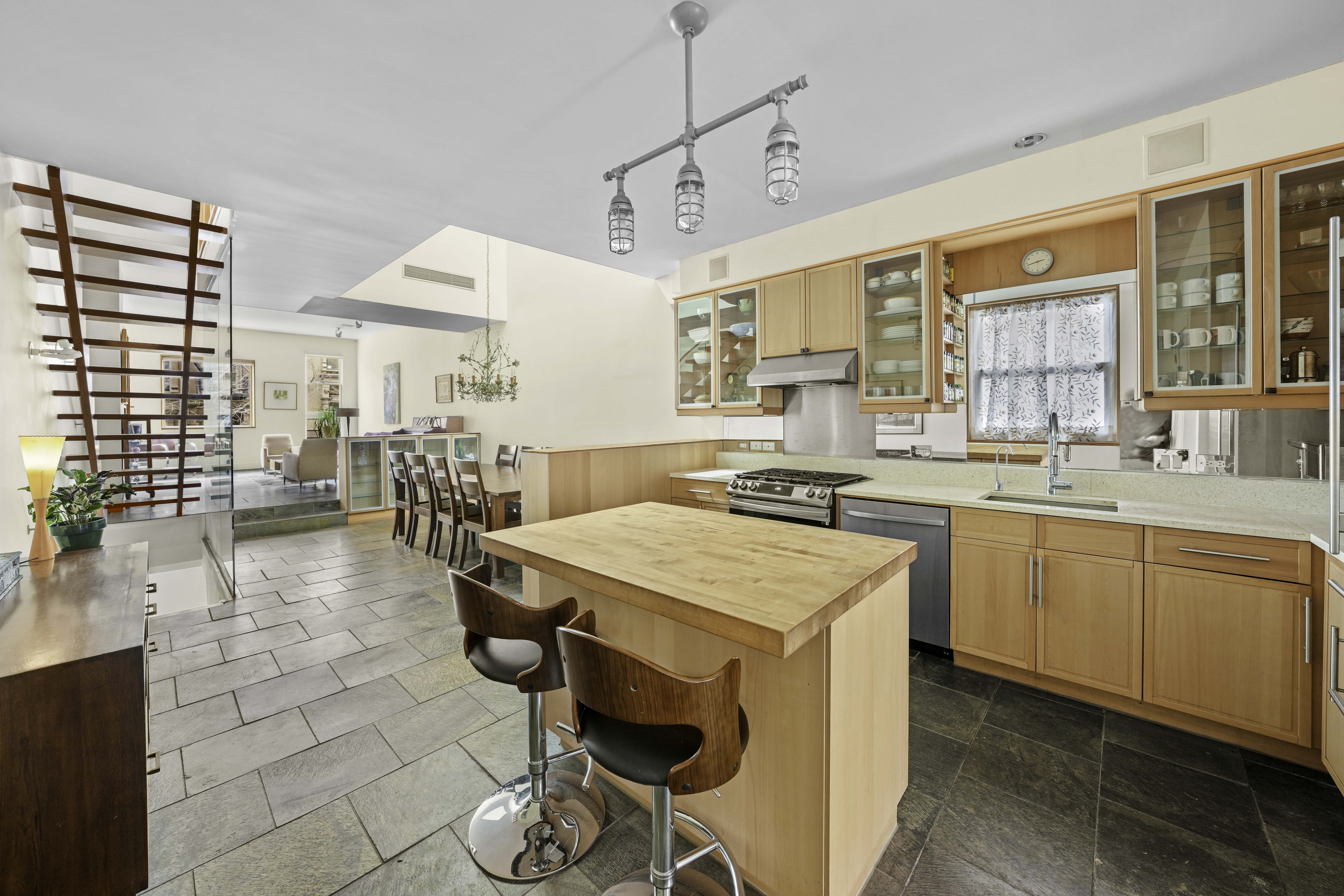 133 West 123rd Street Manhattan, NY 10027 - Photo 12 of 31 a open kitchen with stainless steel appliances kitchen island granite countertop a stove a sink a dining table and chairs with wooden floor