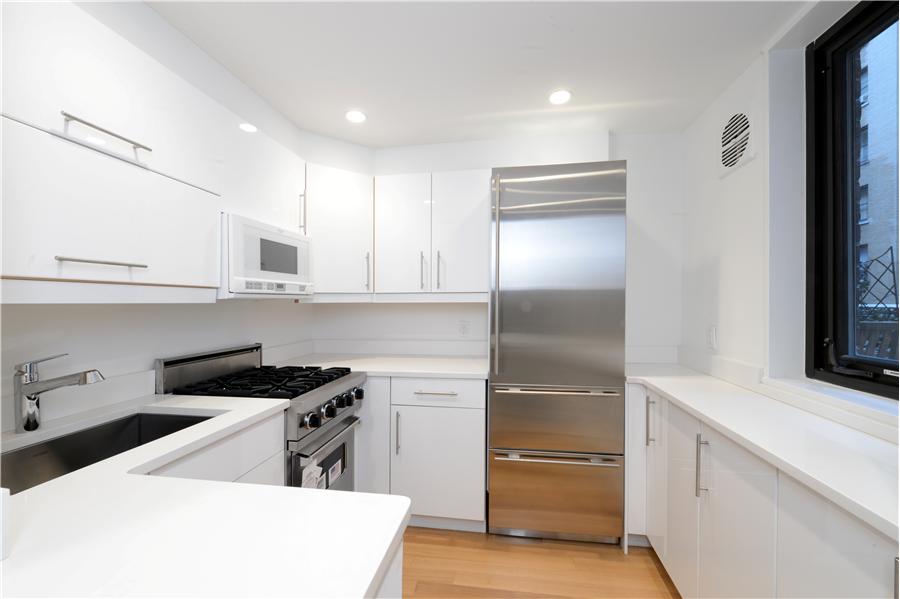 116 Central Park South, Unit 3G Manhattan, NY 10019 - Photo 3 of 5 a kitchen with white cabinets and refrigerator