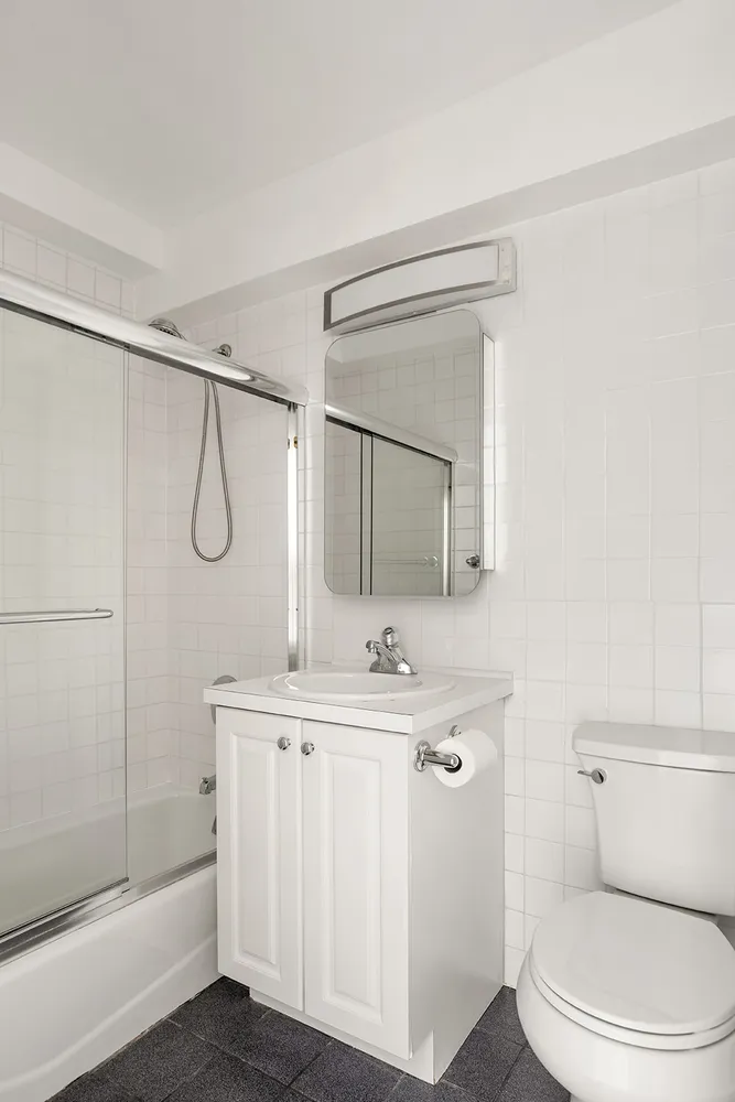 a bathroom with a granite countertop sink a toilet a mirror and shower
