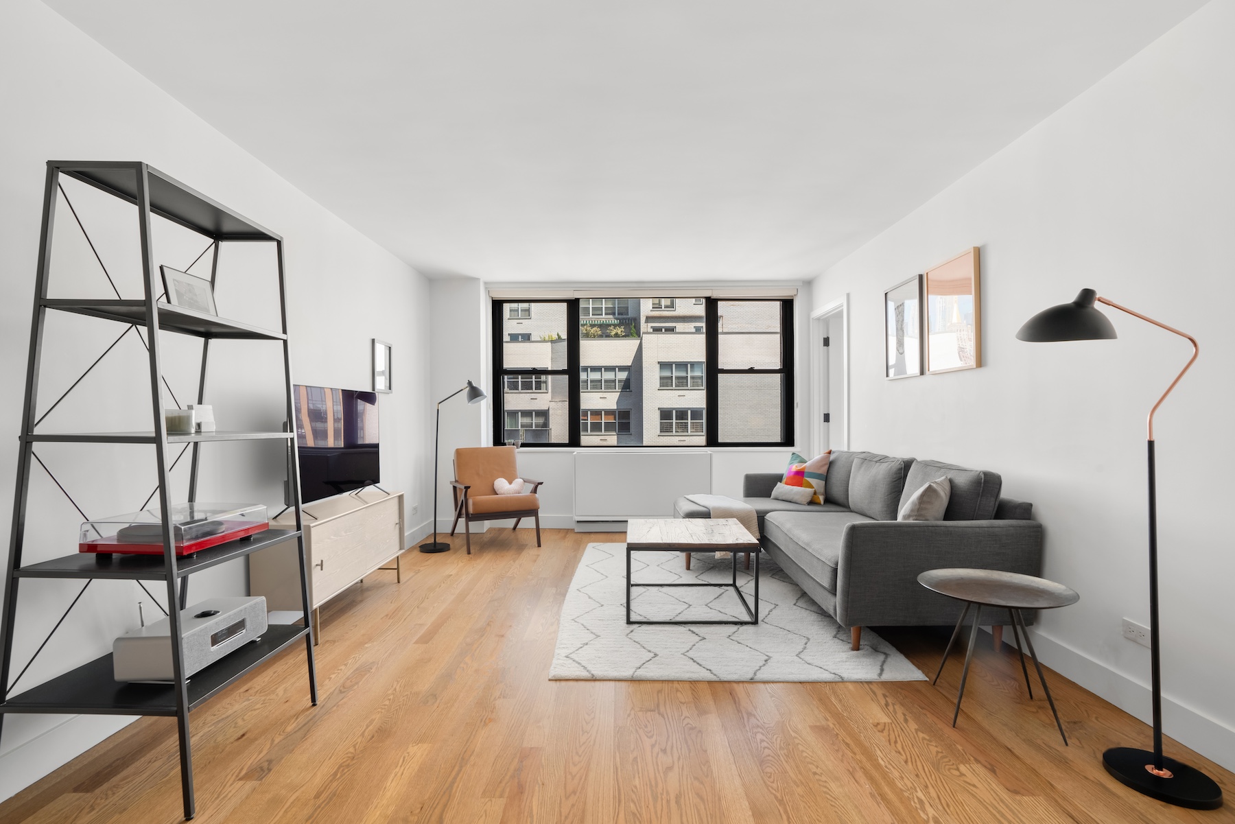 201 East 17th Street, Unit 16H Manhattan, NY 10003 - Photo 4 of 16 a living room with furniture a rug and a floor to ceiling window