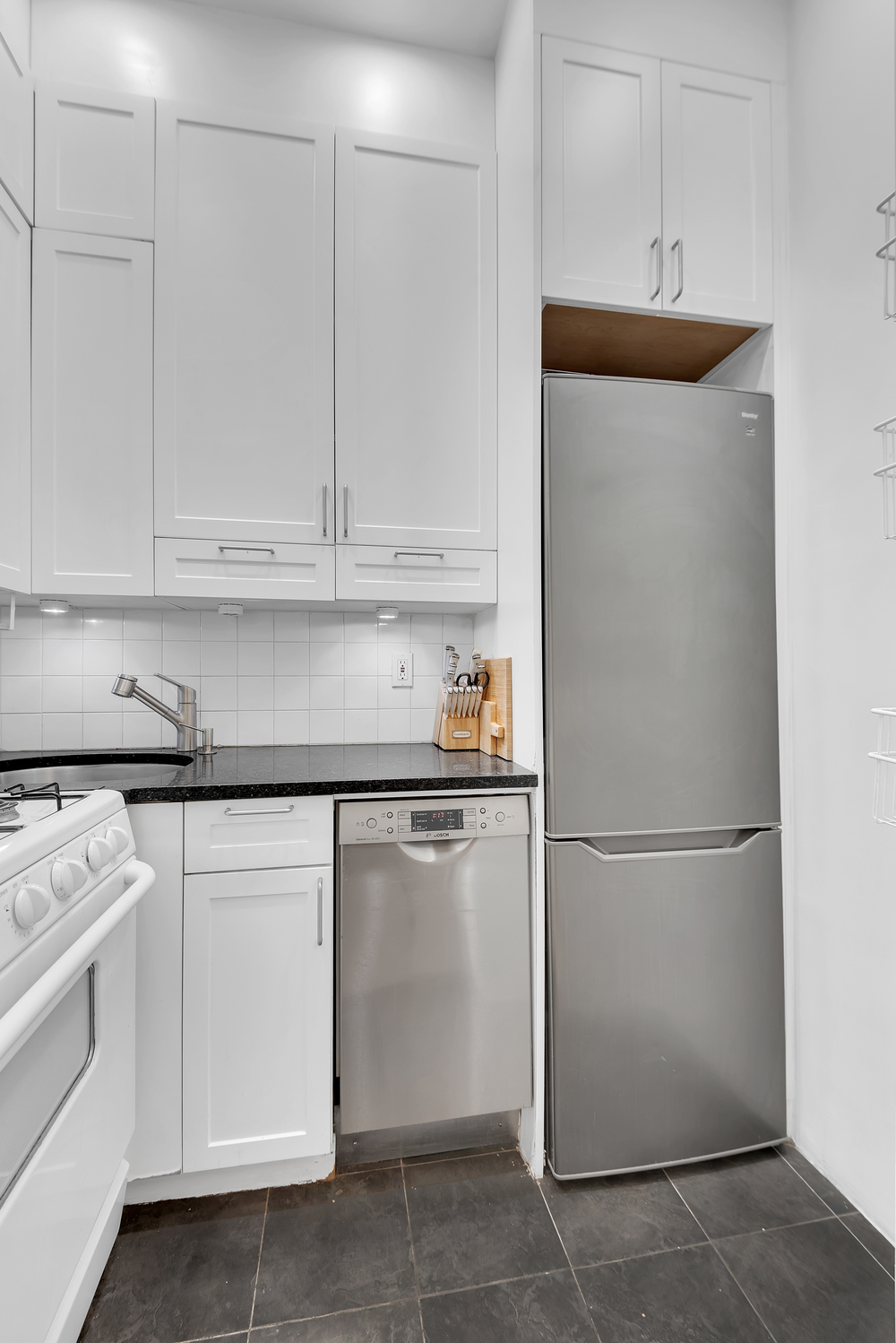 244 East 60th Street, Unit 3B Manhattan, NY 10022 - Photo 4 of 6 a kitchen with white cabinets and white appliances