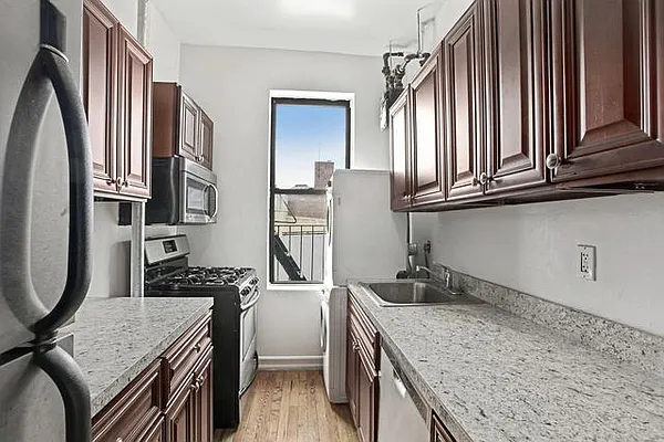401 West 47th Street, Unit 18 Manhattan, NY 10036 - Photo 3 of 5 a kitchen with stainless steel appliances granite countertop a sink stove and refrigerator