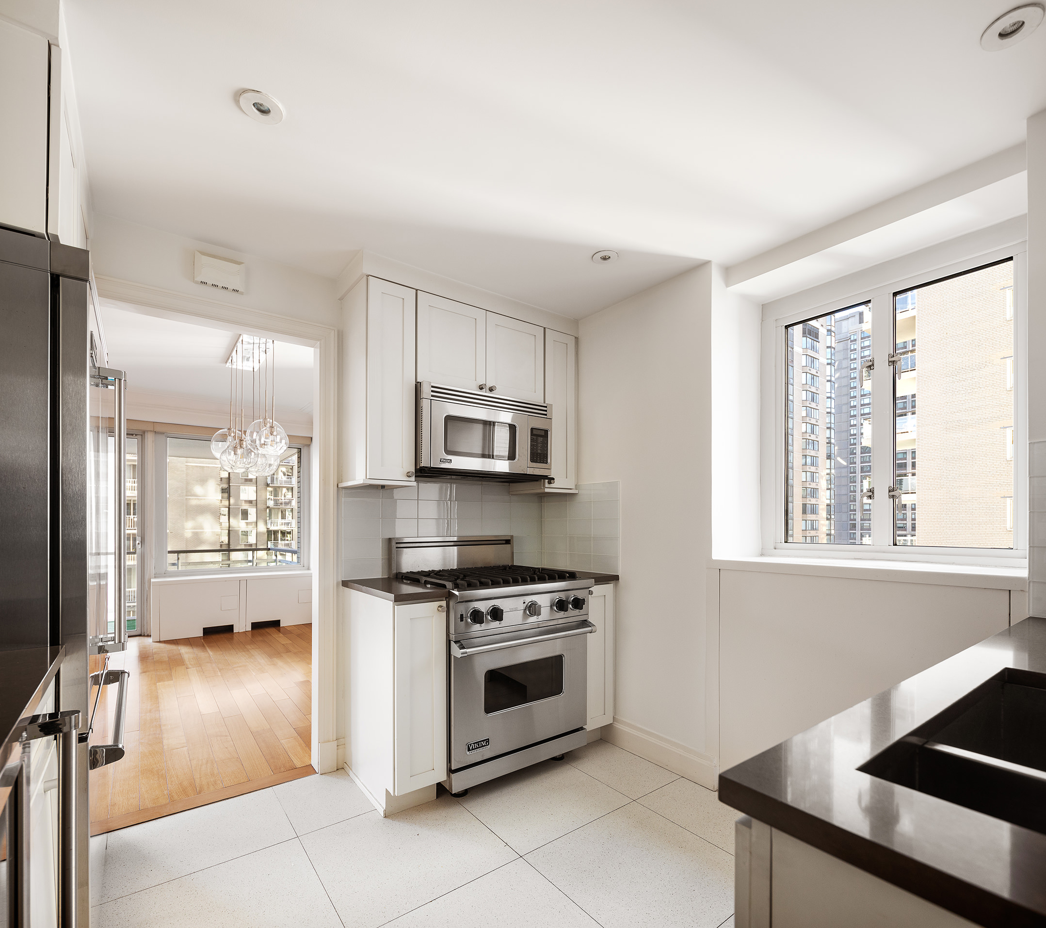 200 East 66th Street, Unit D1203 Manhattan, NY 10065 - Photo 4 of 24 a kitchen with stainless steel appliances a stove a sink and a microwave