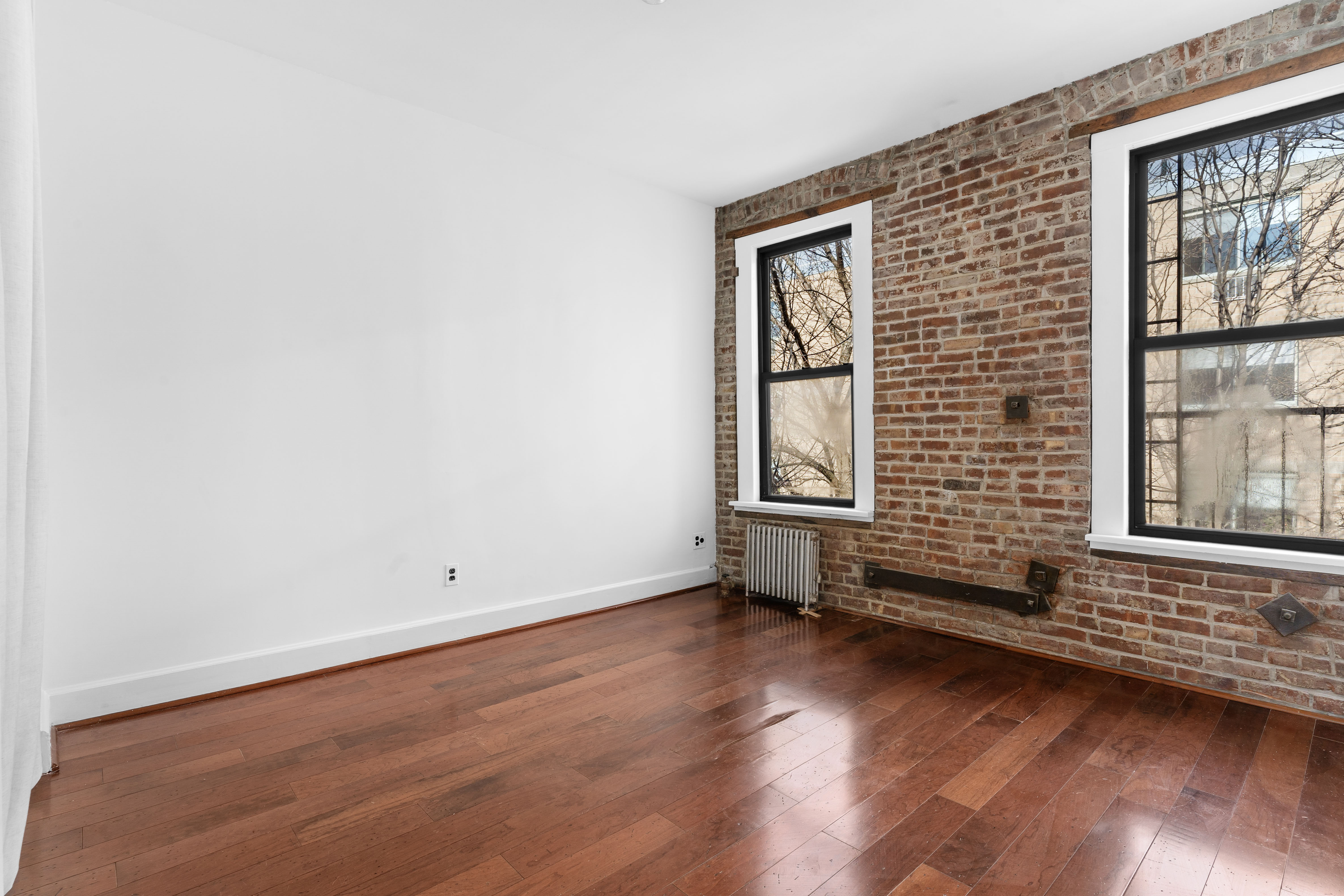 199 East 7th Street, Unit 4E Manhattan, NY 10009 - Photo 2 of 13 an empty room with wooden floor and windows