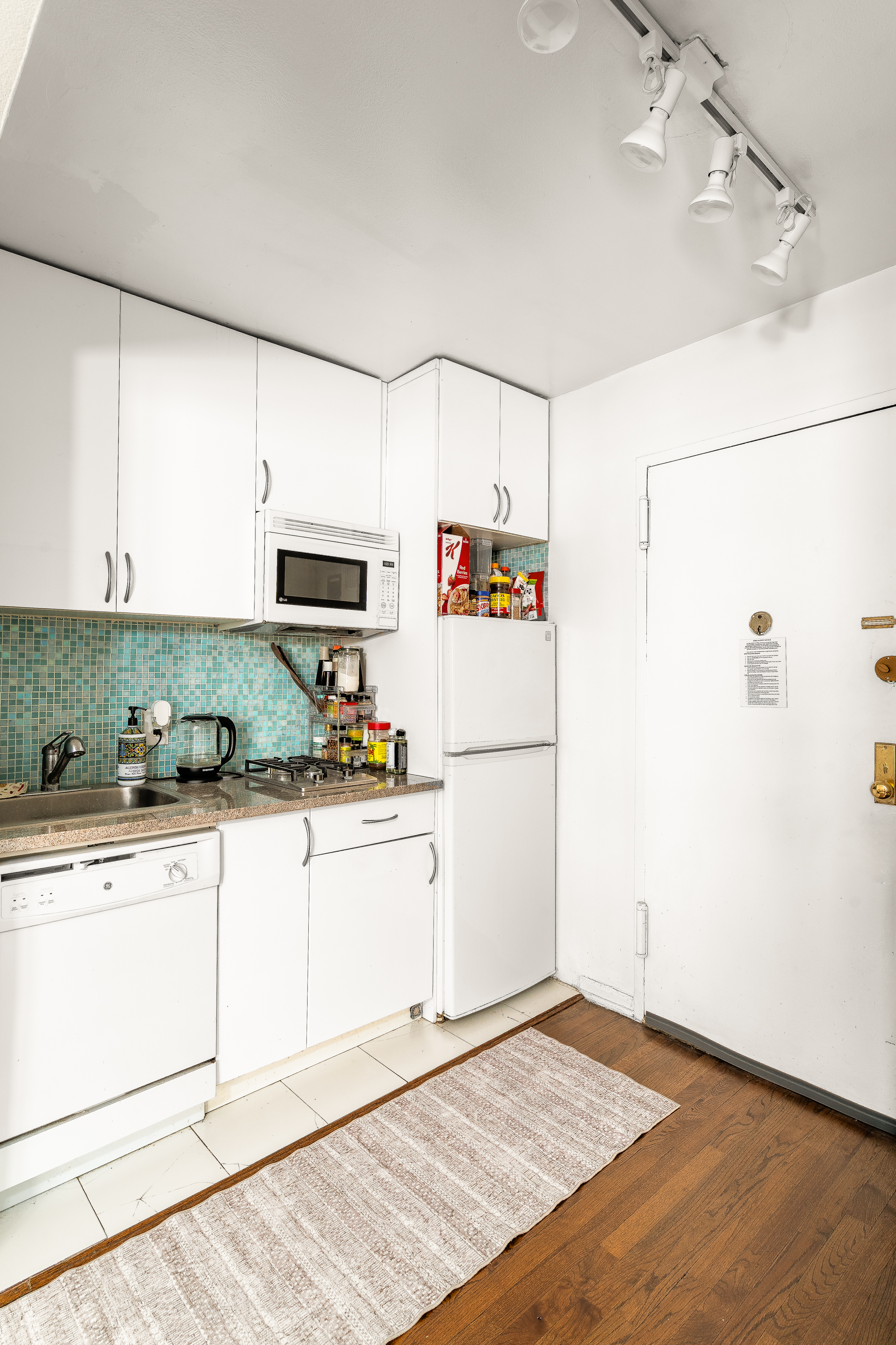 1420 York Avenue, Unit 6J Manhattan, NY 10021 - Photo 9 of 13 a kitchen with granite countertop a refrigerator a stove a sink and white cabinets