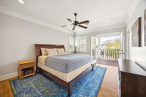 a bedroom with a bed a large window with wooden floor and a rug