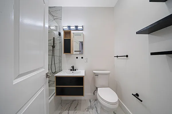 30 Marconi Place, Unit 2 Brooklyn, NY 11233 - Photo 7 of 11 a bathroom with a toilet a sink and mirror