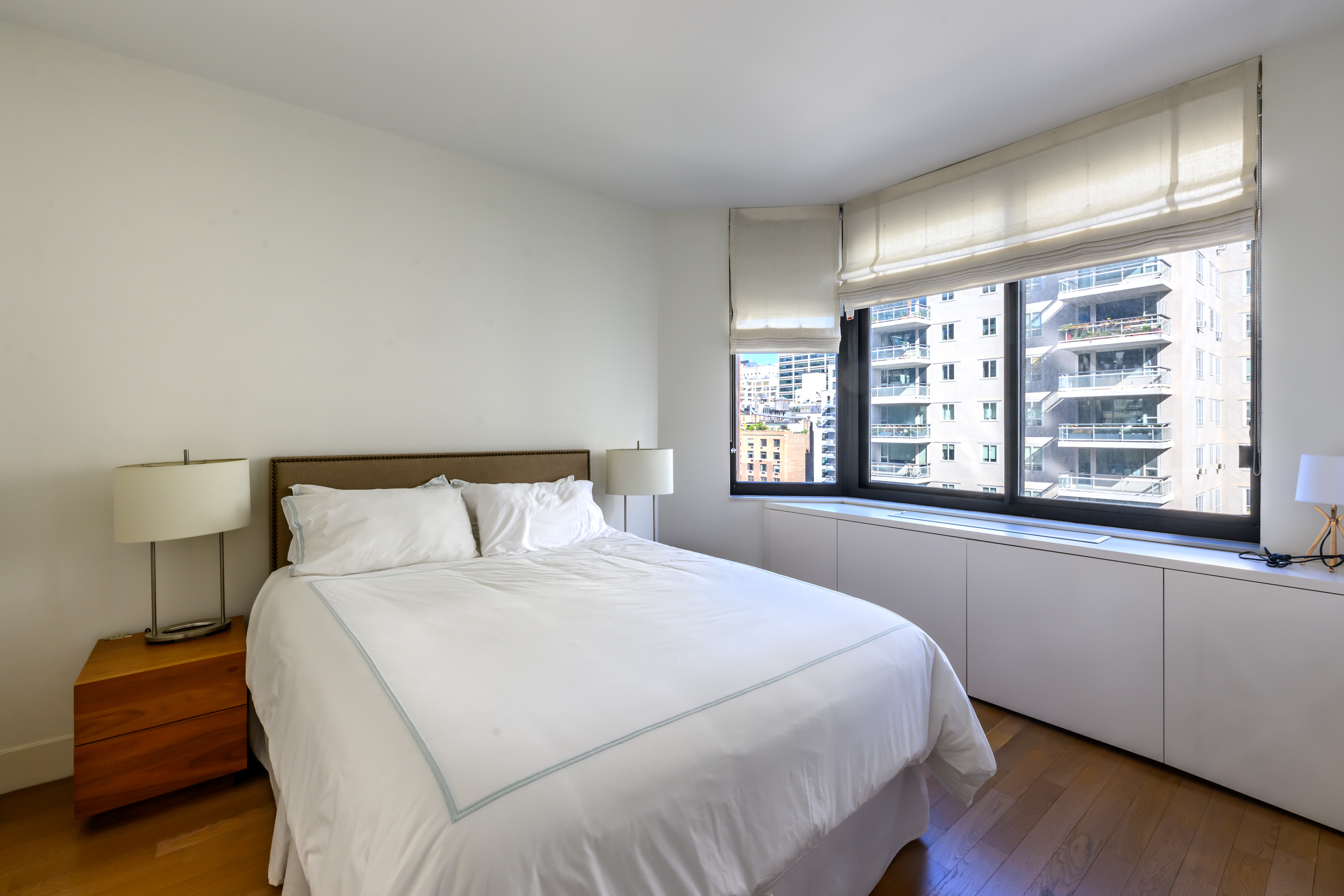 200-210 East 65th Street, Unit 11D Manhattan, NY 10065 - Photo 9 of 15 a bedroom with a large bed and a large window