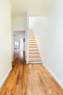 a view of a hallway with wooden floor and staircase
