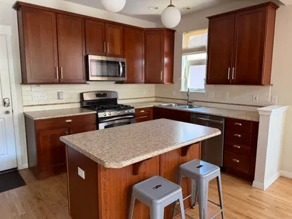 a kitchen with granite countertop a sink a stove counter space and cabinets