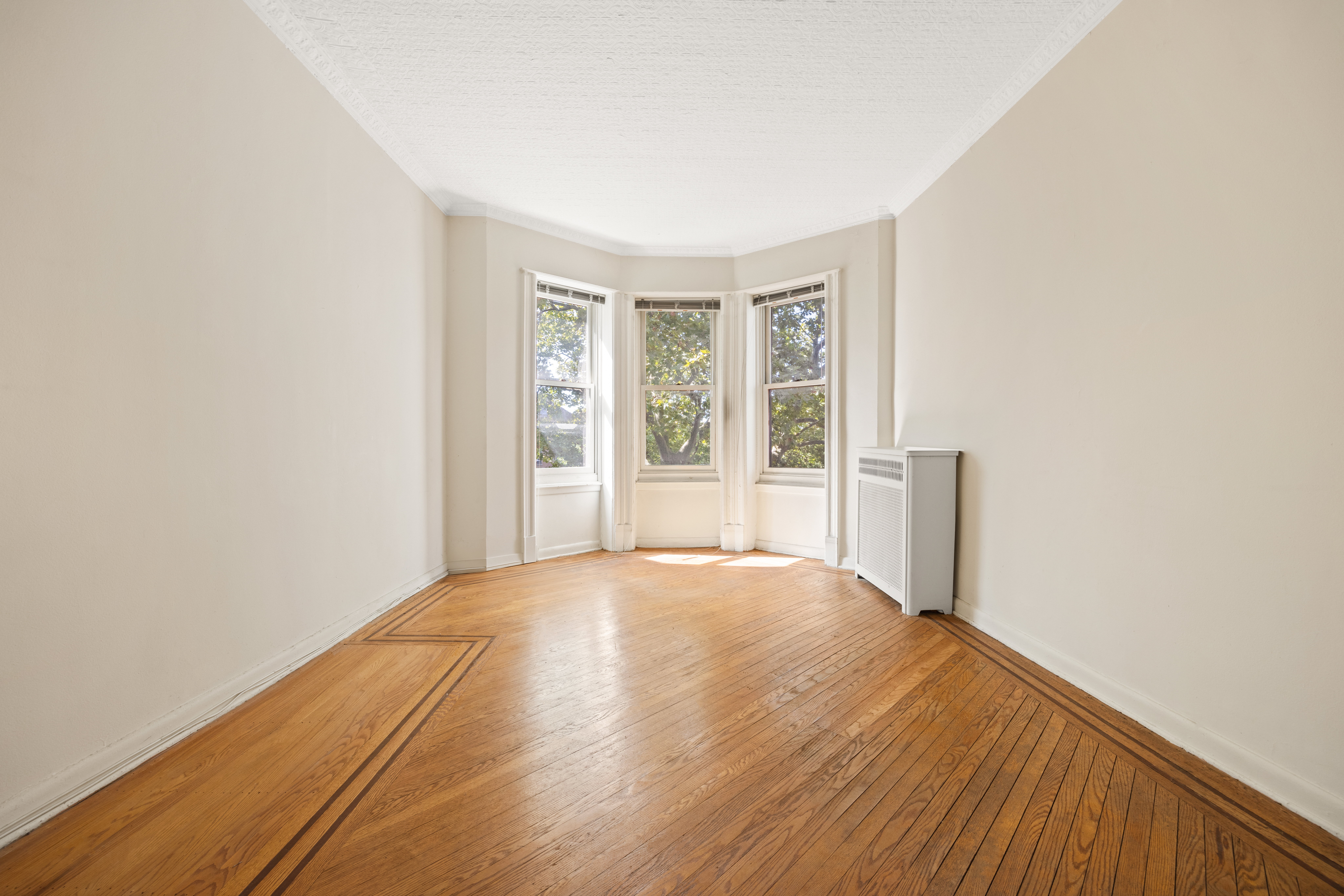 273 Windsor Place Brooklyn, NY 11218 - Photo 17 of 29 an empty room with wooden floor and windows