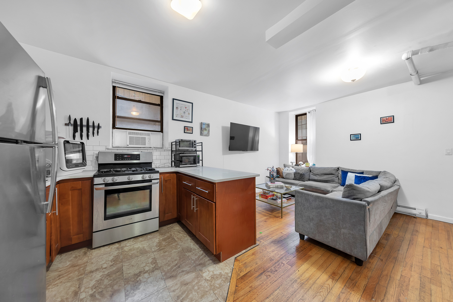 224 East 11th Street, Unit GARDEN Manhattan, NY 10003 - Photo 2 of 6 a living room with stainless steel appliances furniture and a flat screen tv