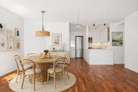 a view of a dining room and livingroom with furniture wooden floor a chandelier