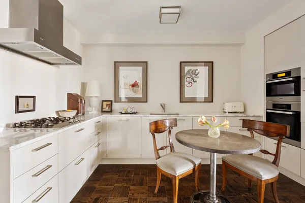 a kitchen with a dining table chairs and white appliances