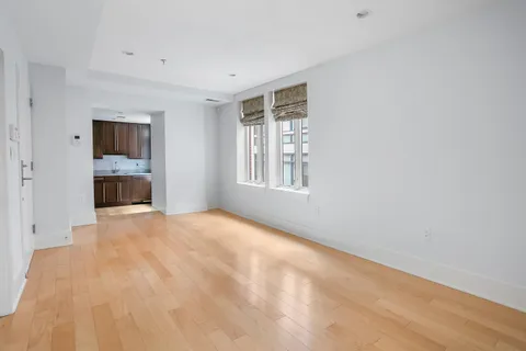 a view of an empty room with a window and a kitchen