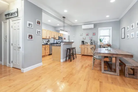 a room with stainless steel appliances lots of wooden furniture a dining table and chairs with wooden floor