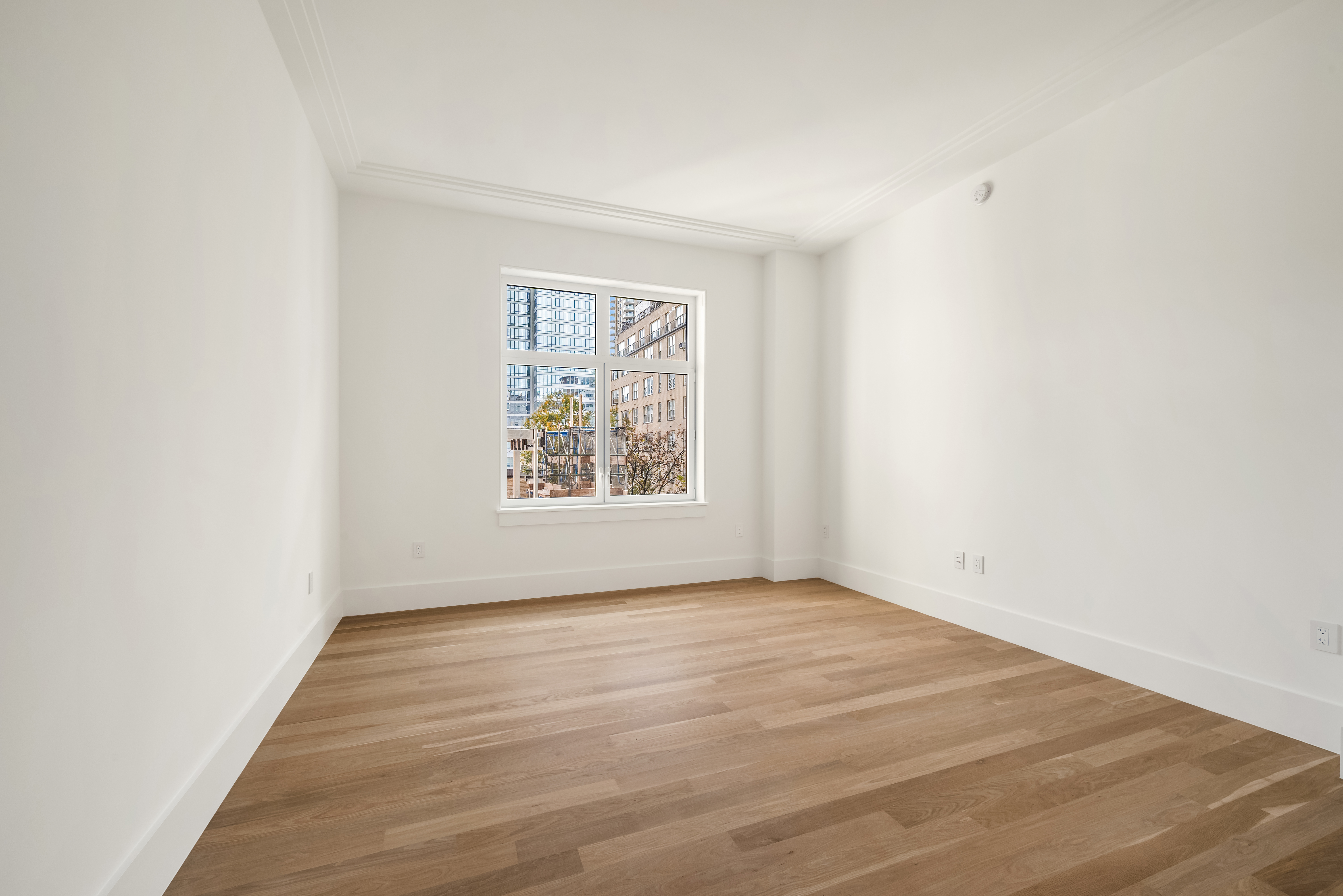 200 East 75th Street, Unit 6C Manhattan, NY 10021 - Photo 4 of 11 an empty room with wooden floor and windows