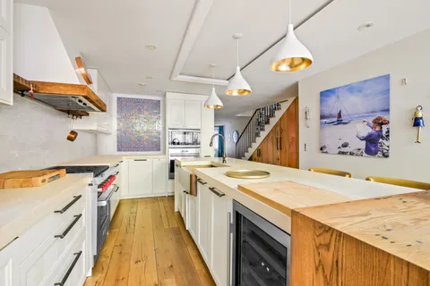 a open kitchen with a stove a sink and a wooden floor