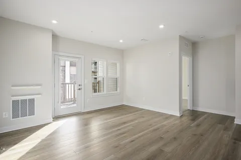 a view of an empty room with wooden floor and a window