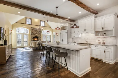a kitchen with stainless steel appliances granite countertop a table chairs stove and wooden floor