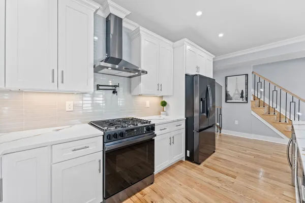 a kitchen with stainless steel appliances granite countertop a stove a refrigerator and a white cabinets
