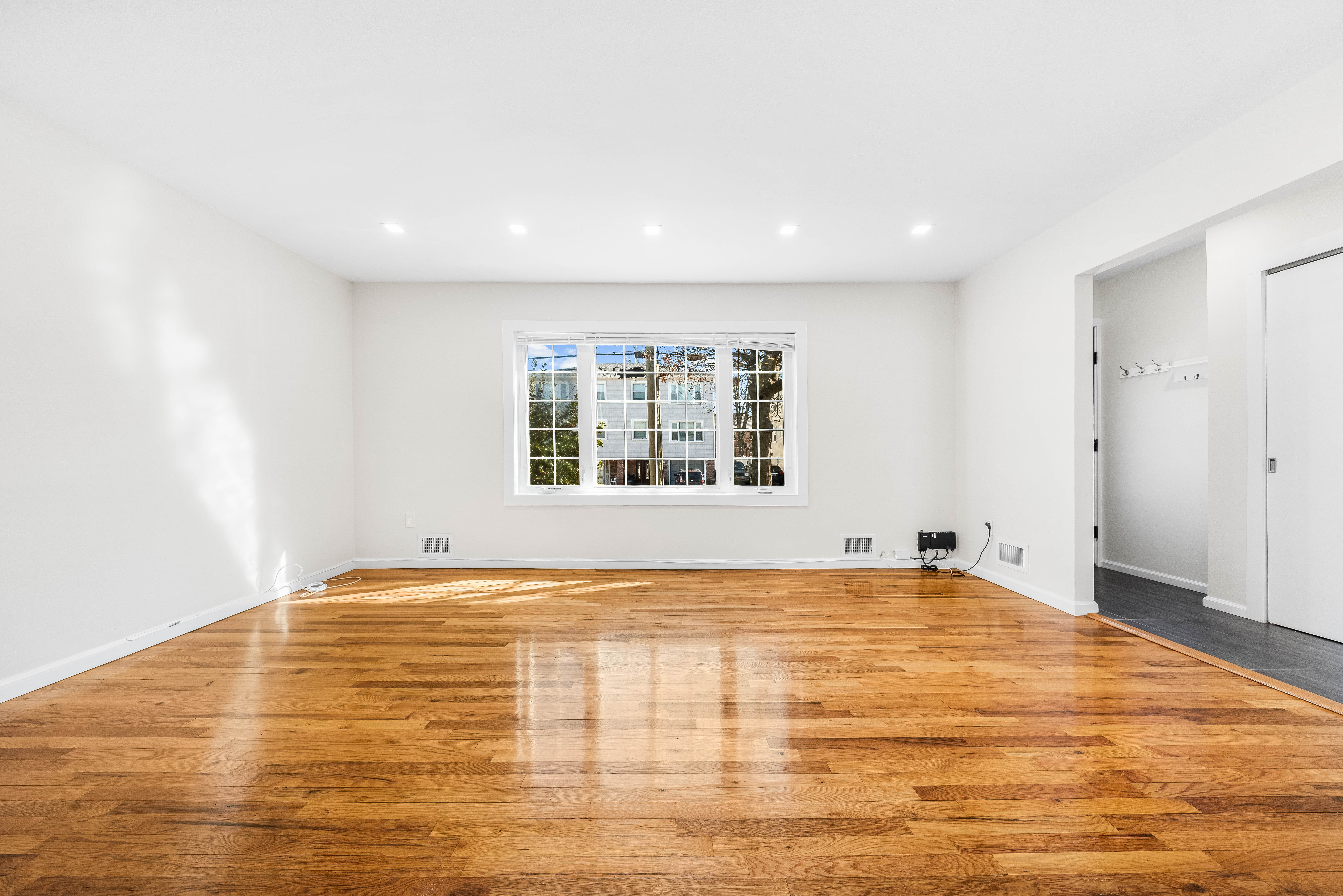 15-80 209th Street, Unit 2 Queens, NY 11360 - Photo 3 of 21 a view of an empty room with wooden floor and a window