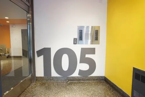 a view of a brick house with a large tree and wooden fence