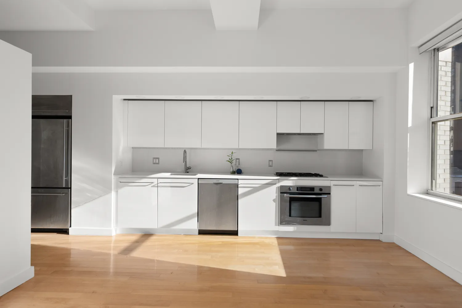 a kitchen with a sink cabinets stainless steel appliances and a window