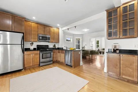 a kitchen with stainless steel appliances granite countertop a refrigerator a stove a sink a oven with white cabinets and wooden floor