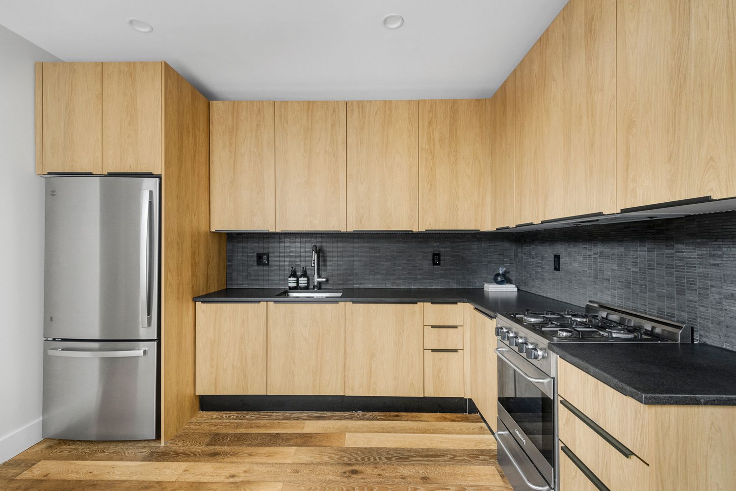 249 Hull Street, Unit C Brooklyn, NY 11233 - Photo 6 of 14 a kitchen with stainless steel appliances granite countertop a refrigerator a stove and a sink with wooden cabinets