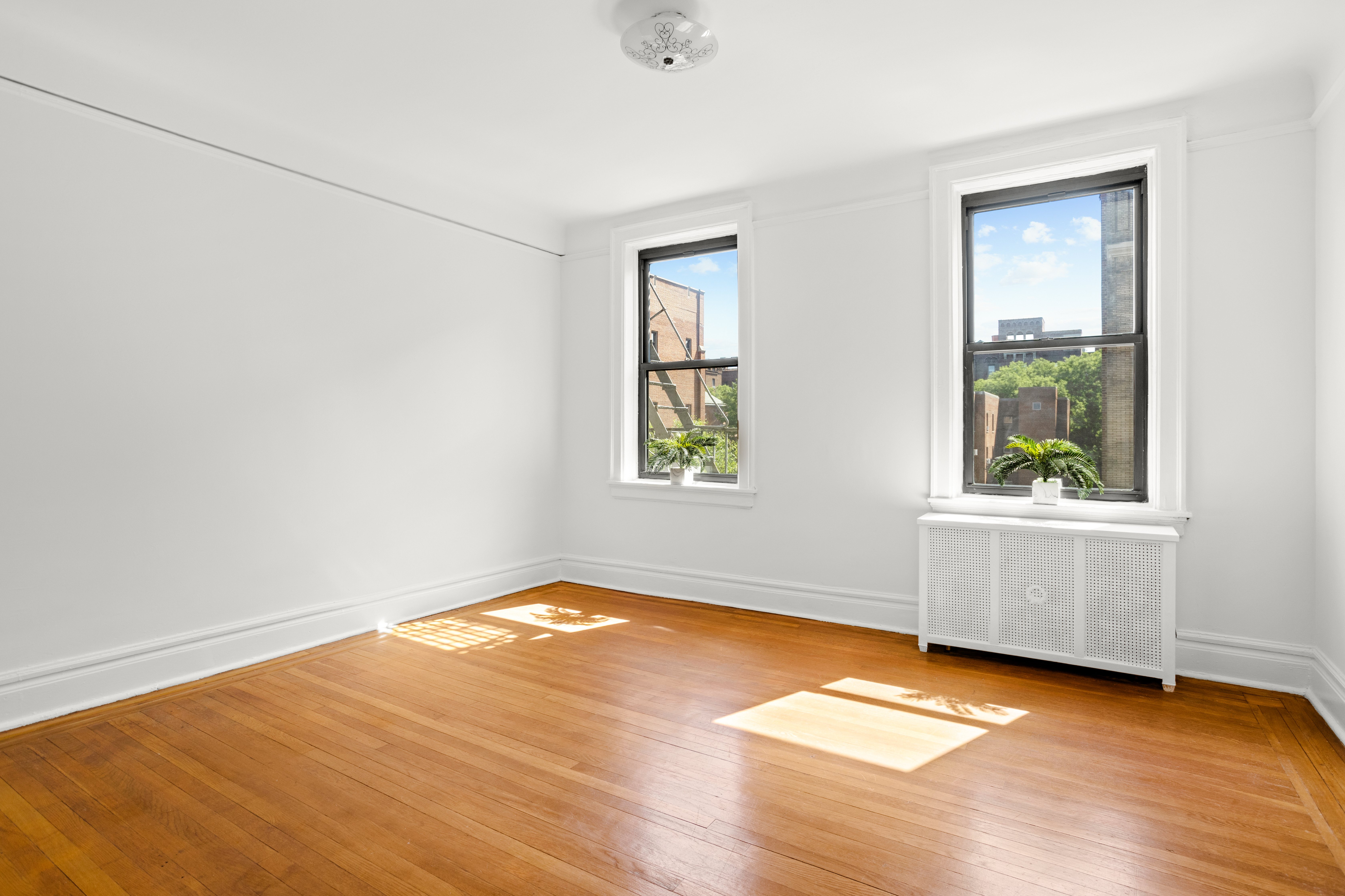 35-30 82nd Street, Unit 32 Queens, NY 11372 - Photo 6 of 11 an empty room with wooden floor and windows
