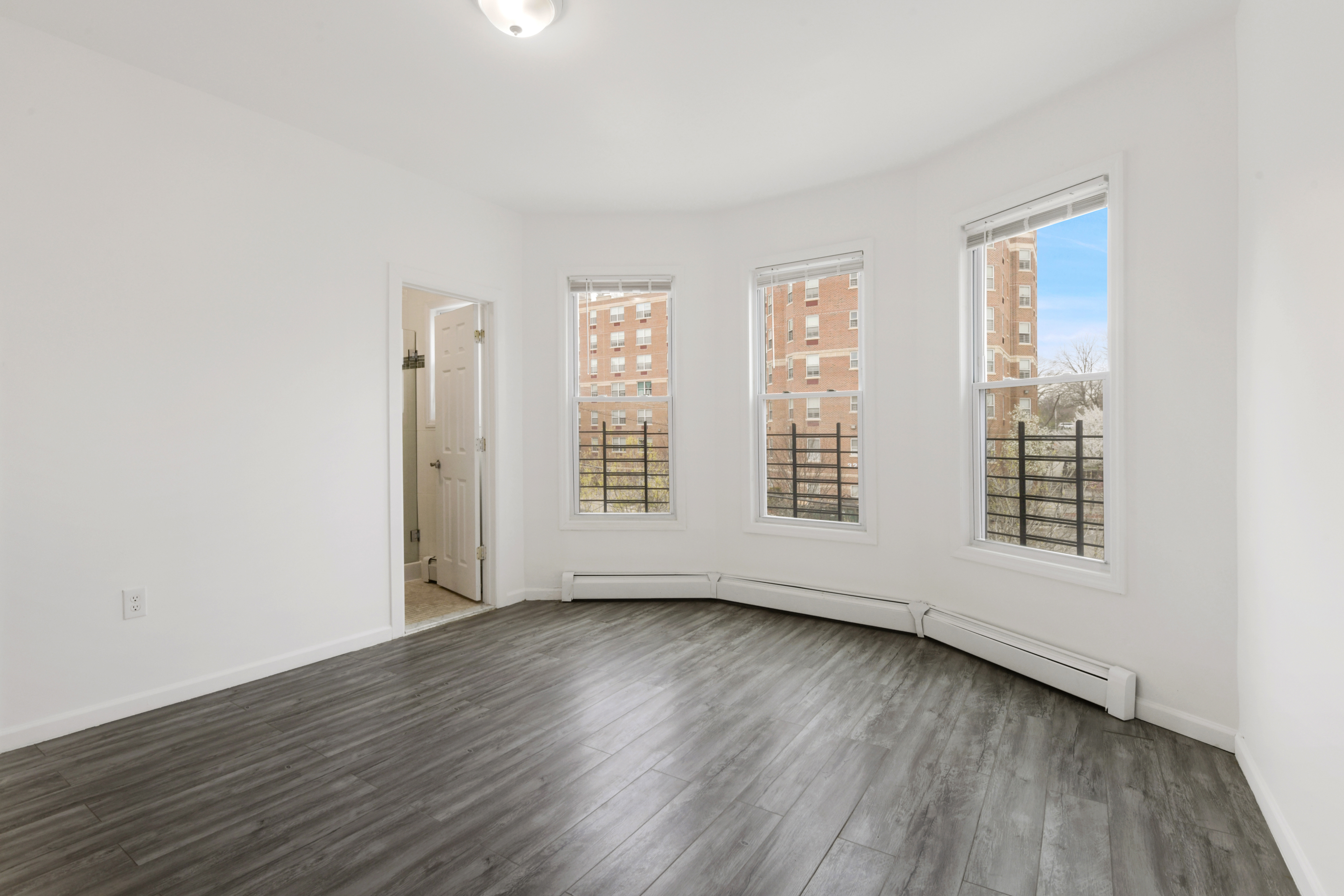 332 East 198th Street, Unit 2 Bronx, NY 10458 - Photo 1 of 10 an empty room with wooden floor and windows