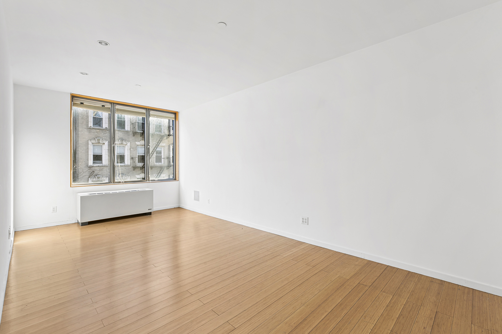 109 Norfolk Street, Unit 4 Manhattan, NY 10002 - Photo 3 of 7 a view of an empty room with wooden floor and a window